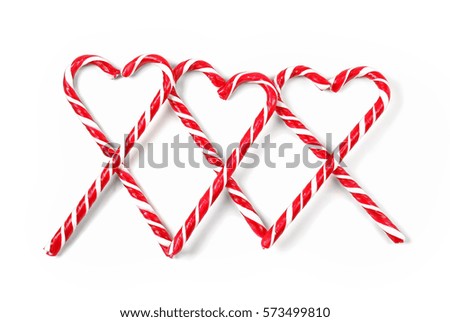 Heart shapes made of candy canes on white background