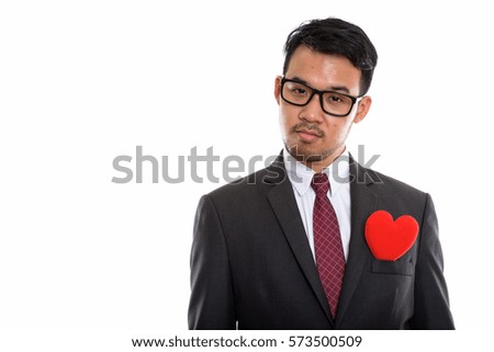Studio shot of young Asian businessman with red heart on chest