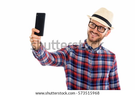 Studio shot of happy young man smiling while taking selfie picture with mobile phone