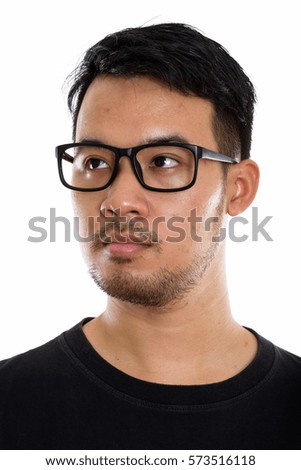 Face of young Asian man thinking while looking at distance and wearing eyeglasses