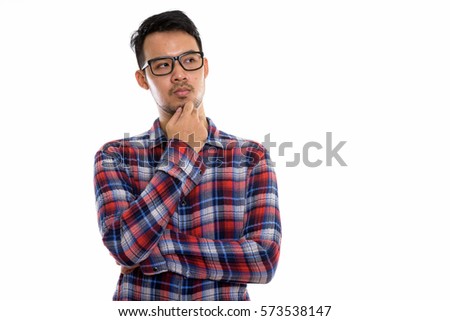 Studio shot of young Asian man thinking while wearing eyeglasses