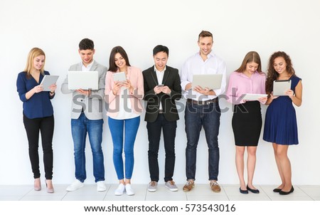 People with gadgets standing near light wall