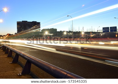Rays of lights, car lights in a street, at dusk Royalty-Free Stock Photo #573545335