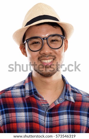 Face of young happy Asian man smiling while wearing eyeglasses and hat
