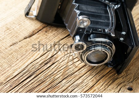 closeup of old folding camera on a textured rustic wooden surface