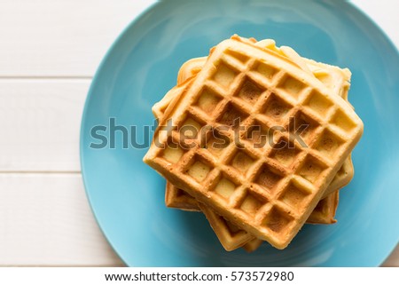 Belgian waffles with honey and cranberries on blue plate. Selective focus Royalty-Free Stock Photo #573572980