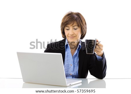 Senior businesswoman using laptop computer while drinking coffee, looking at screen and smiling. Isolated on white background.