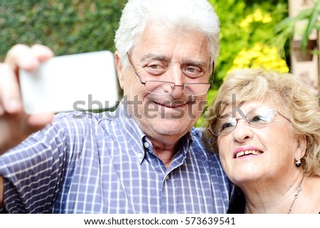 Portrait of an elderly couple taking selfie with smartphone. Outdoors.