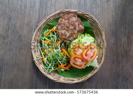 Grill Pork for Hamburger without Bread Served with Tomato, Salad Vegetable and Sunflower Sprout on Bamboo Basket on Wooden Table