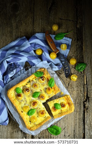 Open pie zhelymi tomatoes and cheese on a plate with a slice cut on a wooden table