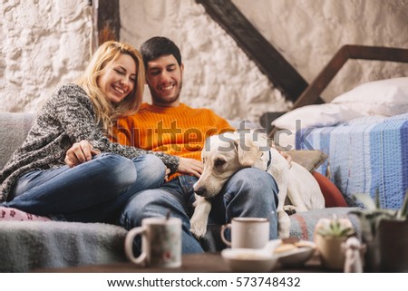 Loving couple relaxing at home and cuddling dog Royalty-Free Stock Photo #573748432