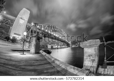 Black and white wide angle view of Sydney Harbour Bridge at night.