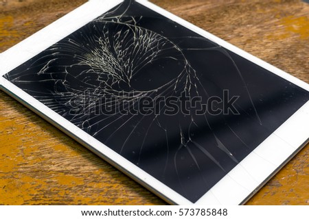 Tablet computer with broken glass screen on the wood background