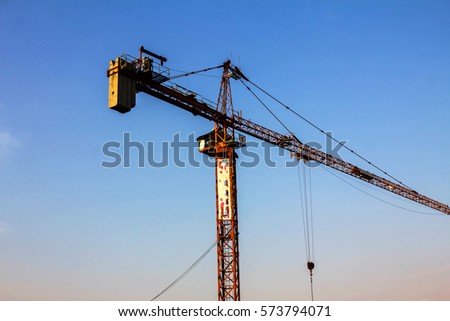Silhouettes of tower cranes against the evening sky. House under