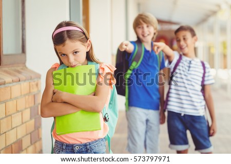 School friends bullying a sad girl in corridor at school Royalty-Free Stock Photo #573797971