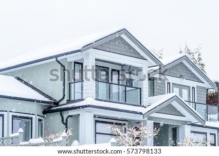 The top of a typical american home in winter. Snow covered roof and nice window. Heavy snowfall over entire picture frame.