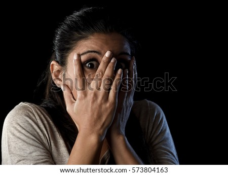 close up portrait young attractive Latin woman desperate and scared isolated on black background looking terrorized and horrified covering her eyes in primal fear emotion face expression Royalty-Free Stock Photo #573804163