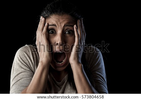 close up portrait young attractive Latin woman desperate and scared isolated on black background looking terrorized and horrified screaming in primal fear emotion face expression Royalty-Free Stock Photo #573804658