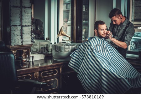 Confident man visiting hairstylist in barber shop Royalty-Free Stock Photo #573810169