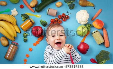 baby surrounded with fruits and vegetables on blue blanket, healthy child nutrition Royalty-Free Stock Photo #573819535