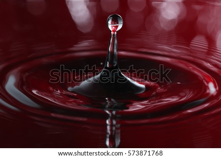water droplet falling and hitting water surface and causing a rebound and explosion