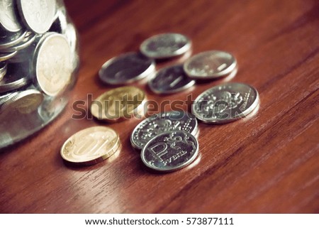 russian coins in the jar and some different coins on the wooden surface