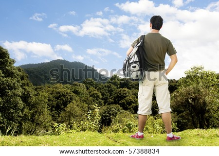 photo of a tourist atop beautiful mountain contemplating the view