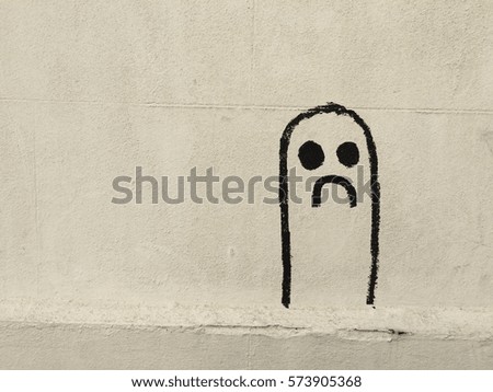 unhappy sad face picture on wall. Drawing on white wall of a thumb shape with unhappy face concept of self isolation during virus pandemic with space to write text