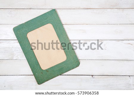 Retro green photo frame on white wooden background. Top view