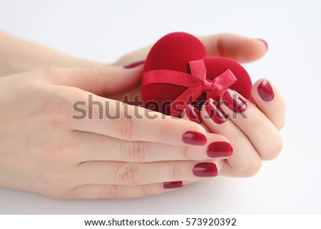 Beautiful female hands with red manicure holding a box of heart-shaped. Happy Valentines day, love concept.