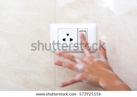 Wet hand of children trun on electric switch. Concept of do not use electricity with wet hand and safety of children. Royalty-Free Stock Photo #573925156