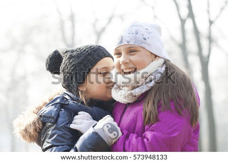 Two little girls with caps and scarves play