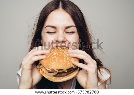 Young woman eating hamburger woman eating junk food, fatty food hamburger.
