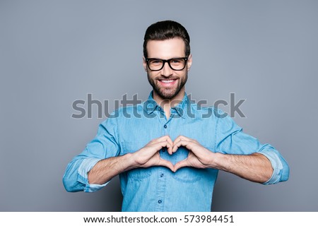 Portrait of happy handsome man in glasses making heart with fingers.