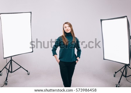 Beautiful young model smiling and posing at the photo studio, softboxes on the background