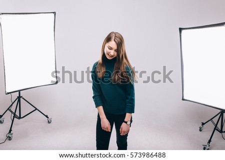 Beautiful young model smiling and posing at the photo studio, softboxes on the background