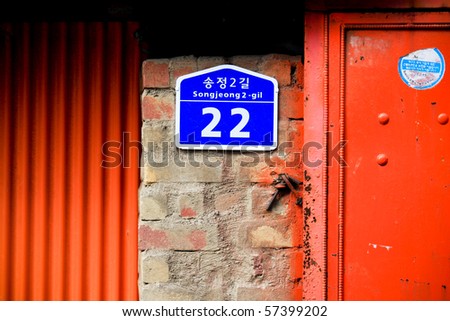 Blue korean street sign on a red wall in South Korea