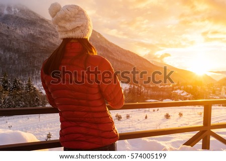 Inspired girl traveler looking to sunset,  watching the sunset in snowy mountains.Place for motivational travel quotes