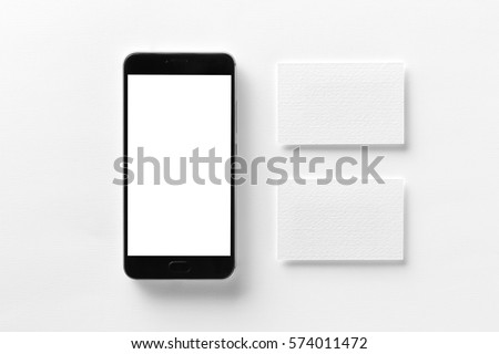 Mockup of cellphone with blank screen and business cards isolated at white paper.