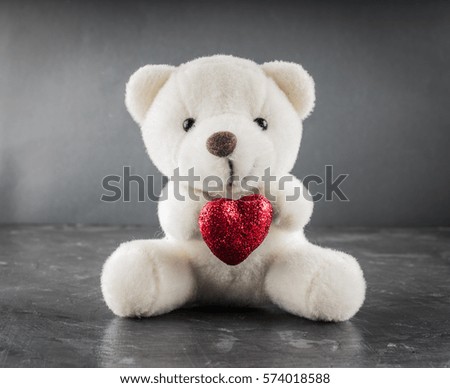 White teddy bear with love letter on red heart on gray background. Say i love you for valentine 's day concept..