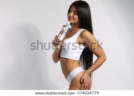 Studio shoot of sporty brunette woman holding bottle of water 