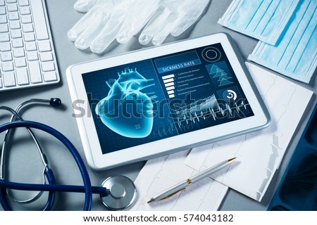 White tablet pc and doctor tools on gray surface Royalty-Free Stock Photo #574043182