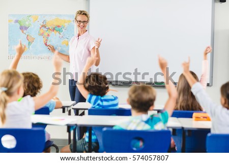 Teacher teaching kids in classroom at school Royalty-Free Stock Photo #574057807