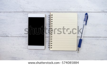 Smartphone and blank notebook on white wood texture background, new technology and manual 