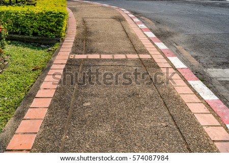 Concrete gravel sidewalk with red and white curb