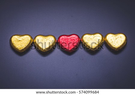 red and gold heart chocolate on blackboard in dark.