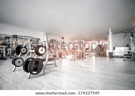 Equipment And Machines At The Empty Modern Gym Room. Fitness Center. Toned image. Royalty-Free Stock Photo #574107949