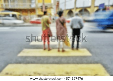 Image blur three people wait no vehicles before crossing the road