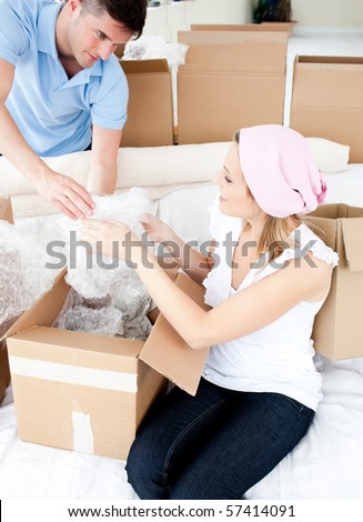 Ambitious young couple unpacking boxes with glasses in their new home