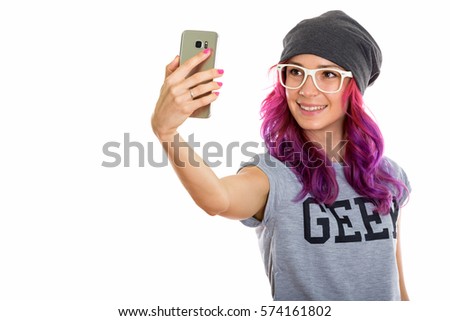 Studio shot of happy geek girl smiling while taking selfie picture with mobile phone